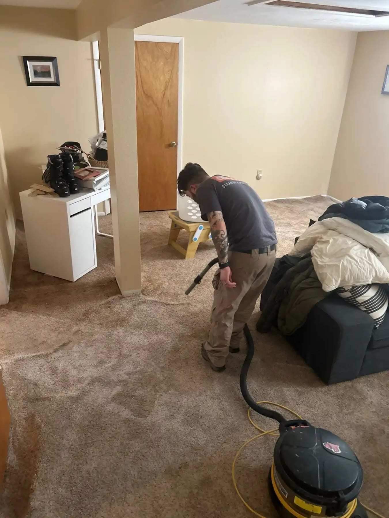 Technician extracting water from bedroom carpet with a wand