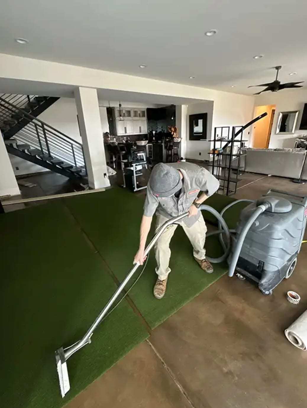 Technician extracting water from turf flooring in an open-plan home