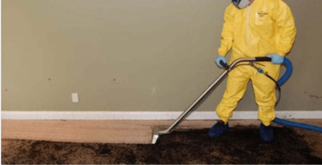 Technician in a protective suit extracting water from a soaked carpet